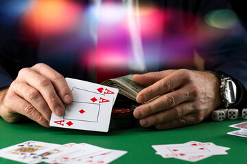 Businessman at green playing table with gambling chips and cards playing poker and blackjack in casino