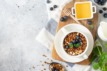 Homemade granola made from buckwheat. Organic buckwheat granola, green buckwheat sprouts, hazelnuts, pumpkin seeds, flax seeds and nutmeg. Granola in a white plate on the light gray kitchen table
