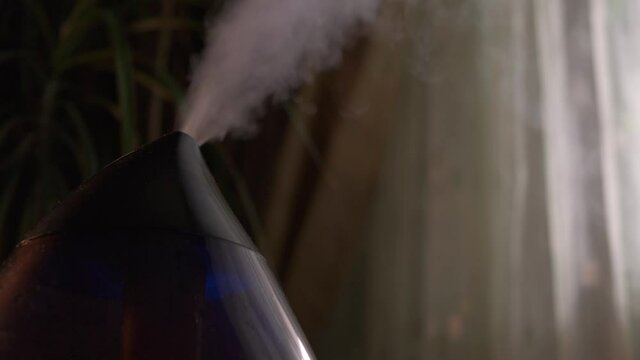 Steam from a modern air humidifier in dark room. Close-up, no people.