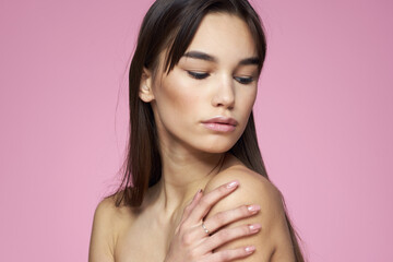 Woman with bare shoulders hair care makeup clean skin pink background