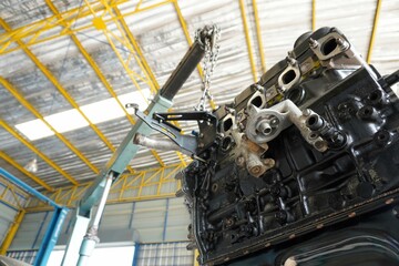 Engine installation on green crane hook on car repair service