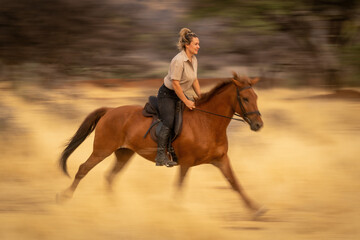 Slow pan of blonde riding through woods