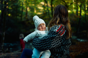 Young mother with baby in the woods on a sunny autumn day