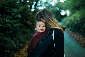 Young mother with her baby in a sling outdoors in nature