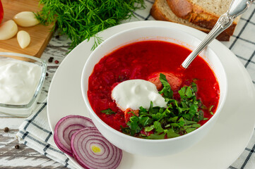 Traditional Ukrainian Russian borscht with garlic and bread. A bowl of red beetroot borscht on a white wooden table. Beetroot soup. traditional slavic cuisine.