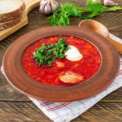 Borsch - traditional Ukrainian and Russian beetroot soup on dark wooden background. Served with rye bread, garlic and salt