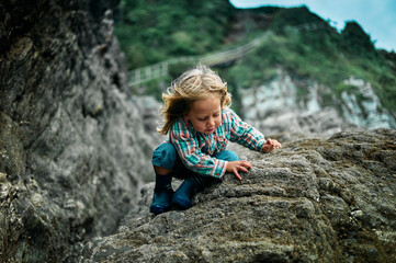 Naklejka na ściany i meble Preschooler climbing on rocks in the autumn