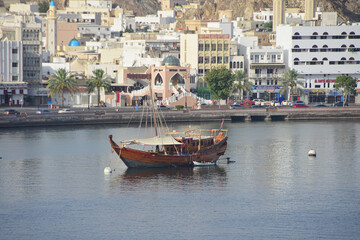 Blick in den Hafen von Muskat im Oman mit einem Schiff aus Holz vor Anker - View of the port of Muscat in Oman with a wooden ship at anchor