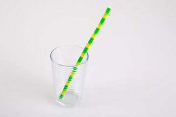 glass with a colorful straw on a grey table background