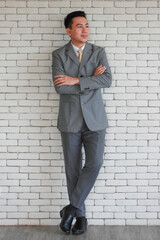 Portrait of a senior elegant standing lean wall and looking businessman in a grey polite suit posing to camera with friendly face and self-confident