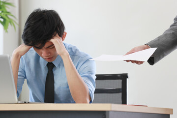 A young junior employee feels headache when the boss abuses him about his wrong or low-quality work.
