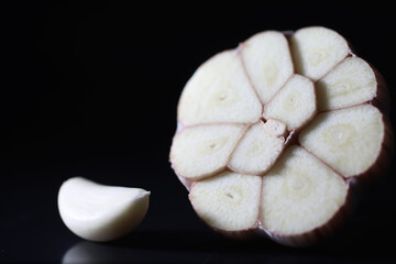 Fresh garlic clove on black background. Garlic is rich in vitamins, useful spring, good spices. Garlic sliced on a dark background. Raw sliced garlic.