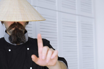 A hilarious parody of an Asian man in a Vietnamese hat with a beard. Portrait. Asian cafe chef.