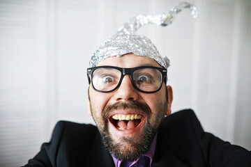 Bearded funny man in a cap of aluminum foil. Concept art phobias.Conspiracy theory. Conspiracy....