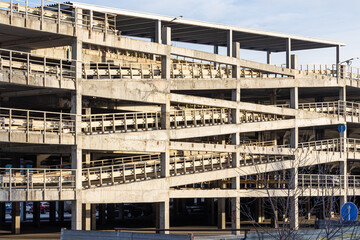 Gray concrete multi-storey parking garage for cars and staircase is outside in winter in a sunny day