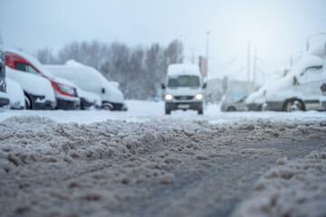 Van drives on muddy snow covered road with slush in springtime