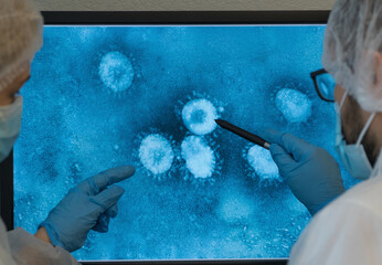 Close up of x-ray of patient with lung pneumonia caused by Coronavirus. Team of doctors at computer...