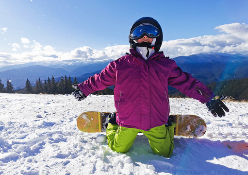 Snowboard Winter Sport. Little kid girl playing with snow wearing warm winter clothes. Winter background