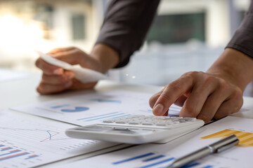 Businessmen use a calculator to calculate income and expenses in order to manage budgets to pay off...