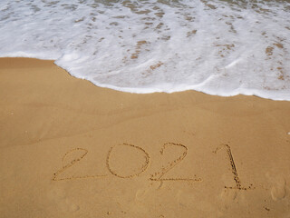 Message Year 2021 written on beach sand for background
