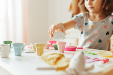 Obraz na płótnie Canvas Little girl playing children tableware