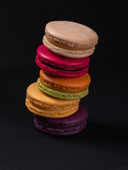 A group of cookies known as macarons on a black background. Small round sweet biscuits with filling. Photo for printing, cooking courses. High quality photo