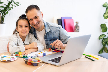 Obraz premium Young father helping her daughter with her school project on laptop at home