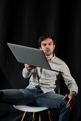 Pleasant positive business man using laptop.Happy smiling man in shirt works on laptop on a dark background