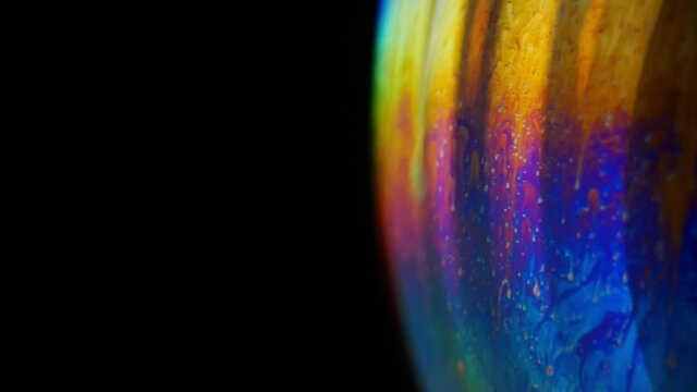 Explosion of multicolored soap bubble on black background as a financial bubble concept. Overvalued asset. Collapse and Explosion