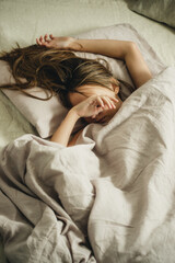 teenage girl sleeping on linen bedding