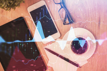 Double exposure of forex chart hologram over desktop with phone. Top view. Mobile trade platform concept.