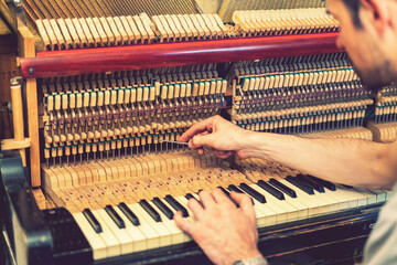 Piano tuning process. closeup of hand and tools of tuner working on grand piano. Detailed view of...