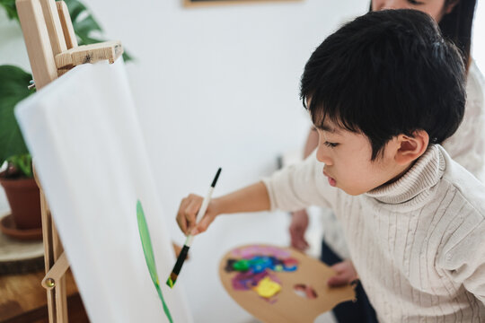 Asian son kid painting on canvas during art class - Focus on child eye - Home school concept