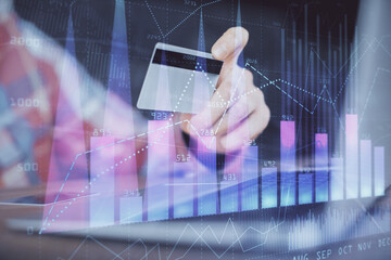 Double exposure of man hands holding a credit card and Forex graph drawing. Stock trading and digital fintech in Internet E-commerce concept.