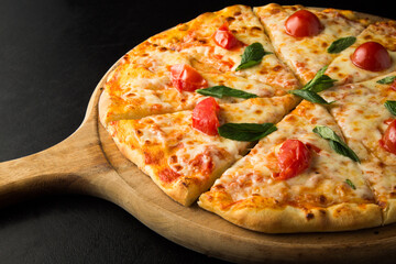 Mozzarella pizza with tomatoes on a wooden pizza plate