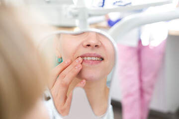 Woman smiles, looks in teeth after treatment at the dentist