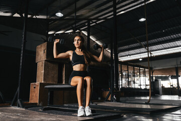 Fit young woman at a crossfit style on dark gray background. Fitness, functional, training, and lifestyle concept