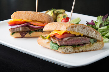 Roast beef sandwiches cut in half in a white plate 