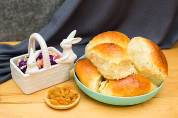 delicious golden buns on a plate, raisins and candy on a wooden table. Homemade baking. View from above. Background