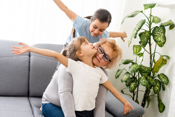 Happy middle-aged mature grandma and little preschooler two granddaughters having fun playing at...