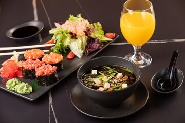 Japanese food, sushi, rolls, soup, salad on black background