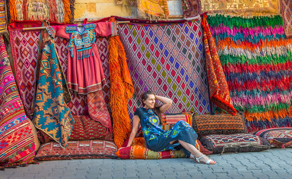 Woman in Turkish market with amazing colorful carpets. Traditionl turkish decoration with colorful ornament. Cappadocia.