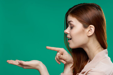 surprised woman holding palms in front of her emotions side view close-up green background
