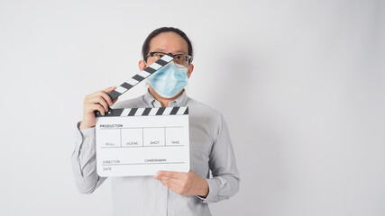 Fototapeta na wymiar Male wear shirt and face mask and hand hold clapper board or movie slate. it use in video production and cinema industry on white background.