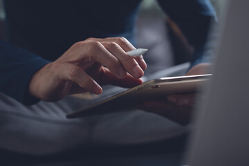 Close up of man hand with stylus pen using digital tablet surfing the internet during working from...