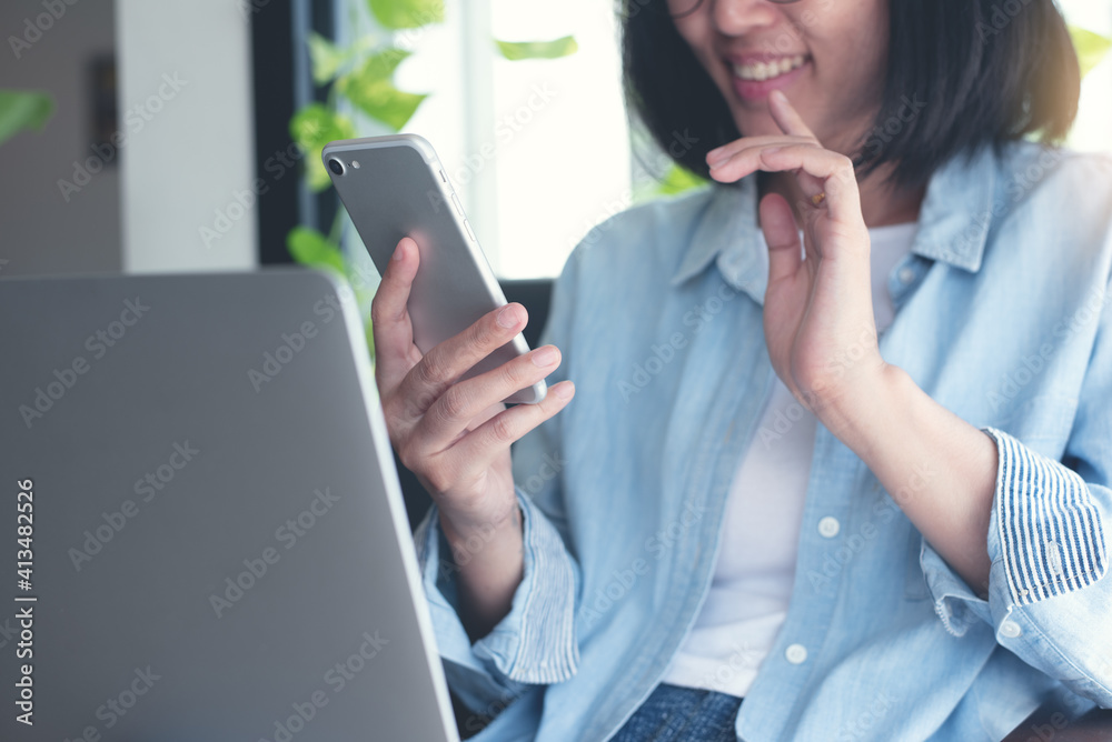 Wall mural Asian casual business woman making facetime video calling via mobile phone online working from home