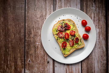 Healthy breakfast toasts with Avocado toast, tomato with whole grain sandwich bread on wood background. Concept of healthy eating, dieting, vegan vegetarian food