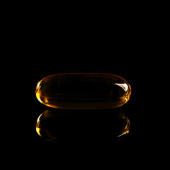 Fish oil concentrate in a soft gelatin capsule to support human health. Omega3 close-up on a black background.