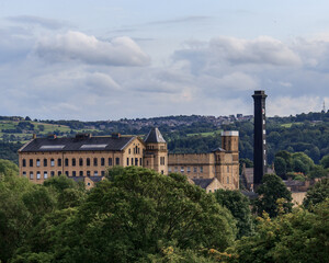 The Victorian textile mill and chimney provide a stark contrast against the green background...