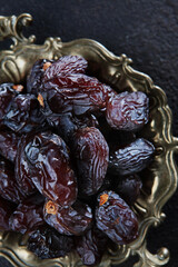Ripe dates on an old copper platter. Juicy dried fruits. Healthy food. Fast food. Food for vegetarians. Vertical photo.